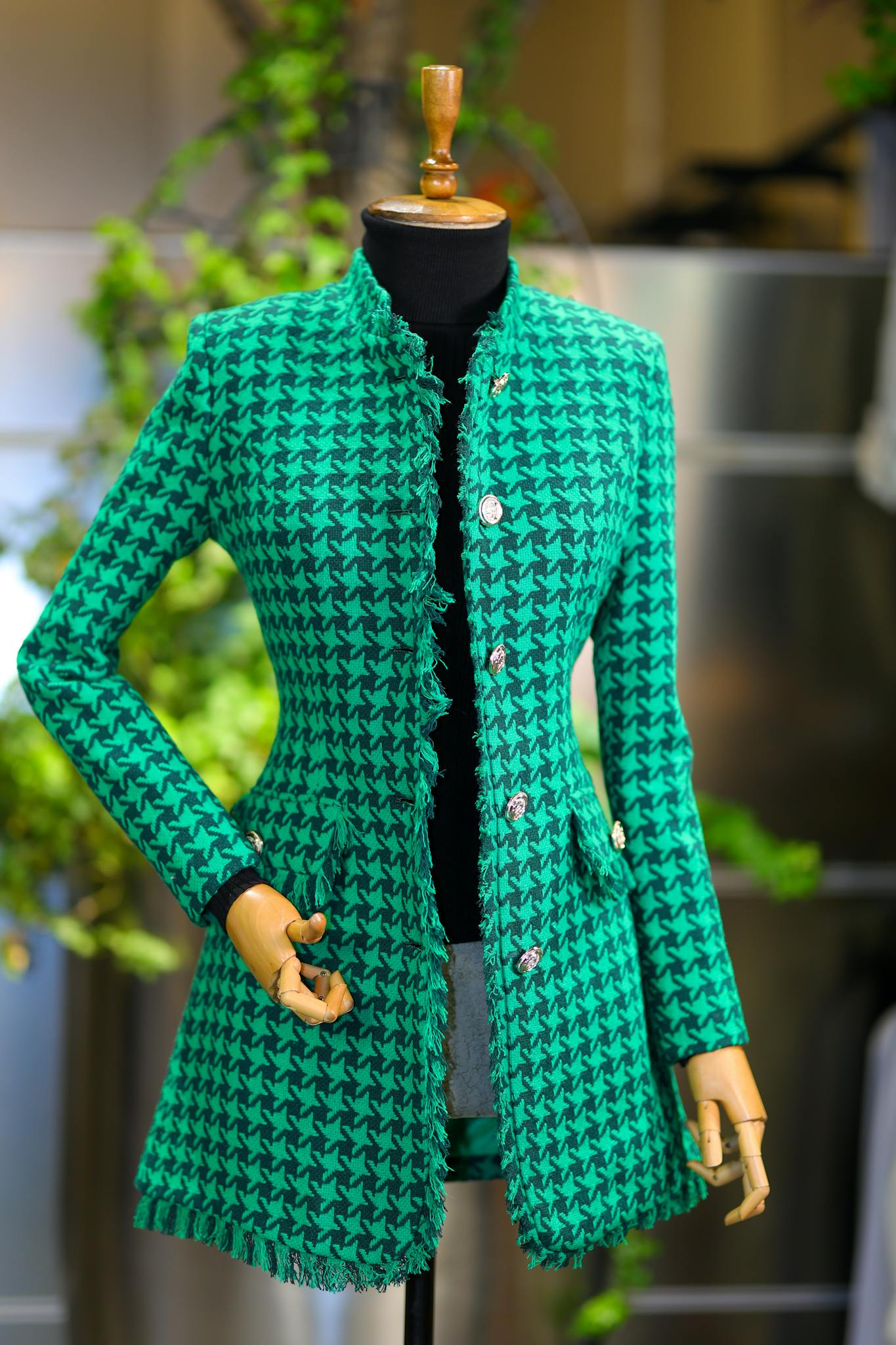 Stylish green houndstooth jacket displayed on a mannequin indoors. Perfect fashion piece.