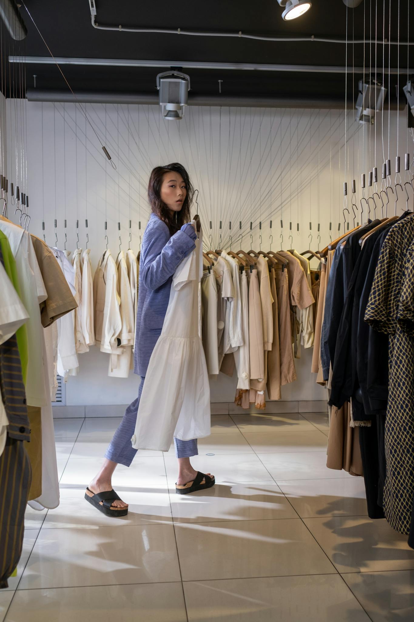 Stylish young woman shopping in a chic clothing boutique, selecting trendy outfits.